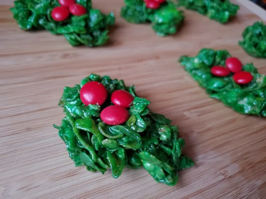 Classic holly wreath cookies on a wooden board.