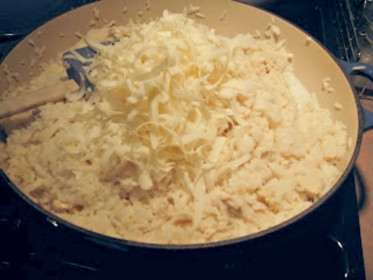 Fresh grated parmesan cheese in a ceramic cast iron skillet over rice and chicken.