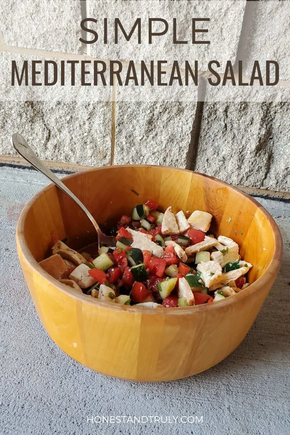 Mediterranean salad sitting near a concrete block wall with text simple Mediterranean salad.