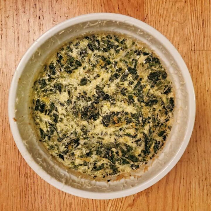 Overhead shot of a whole spinach souffle on wooden background.