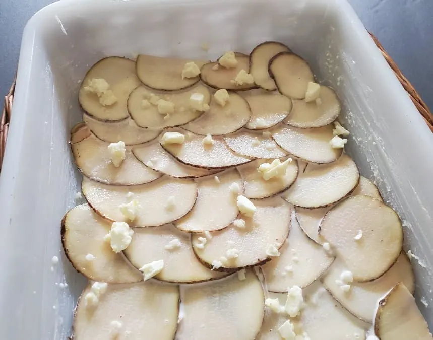 Butter and garlic dotting sliced potatoes