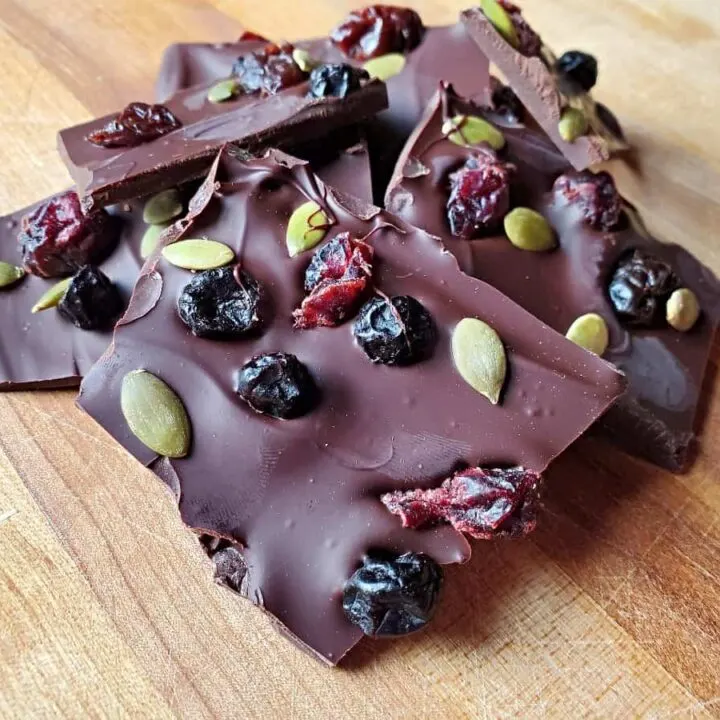 Closeup of dark chocolate bark with dried fruit on a wooden background.