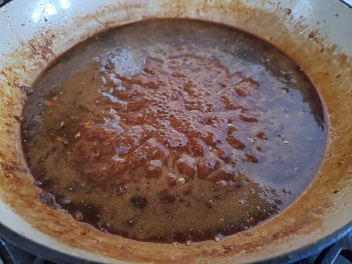 Boiling a honey glaze sauce in a large skillet.