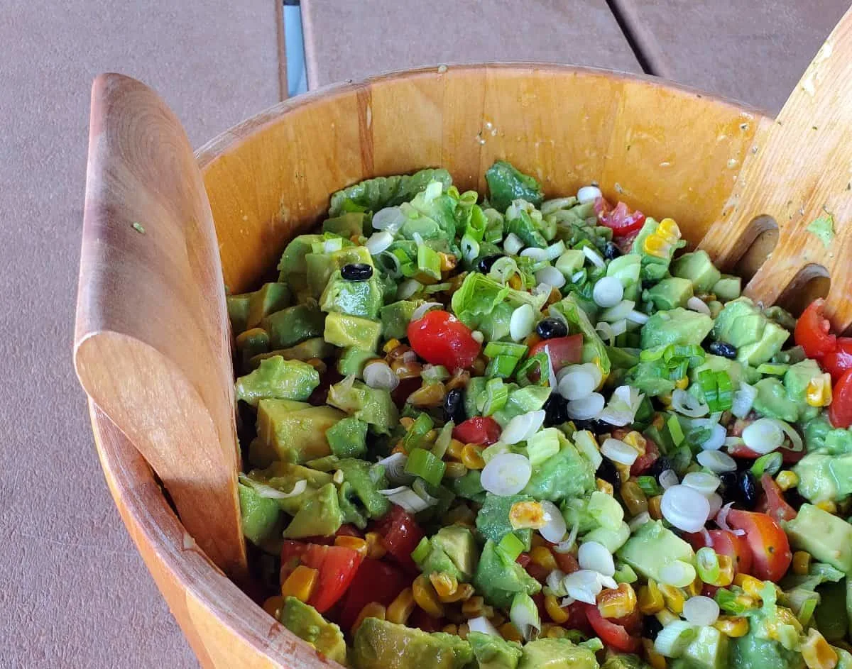 Close up of tomato avocado salad in a wooden bowl.