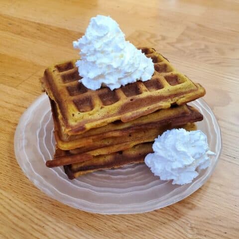 Plate of pumpkin waffles with whipped cream