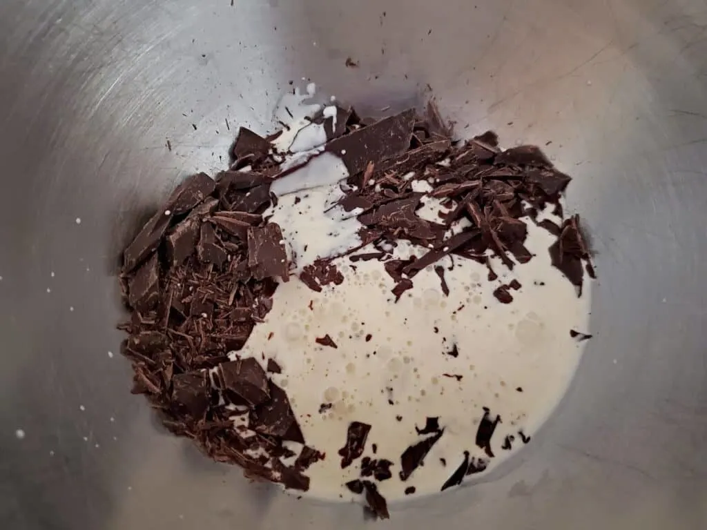 Cream poured over chocolate to melt in a silver bowl.