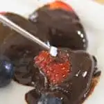 Dipped strawberries on a white plate with fondue fork and text easy dessert fondue.
