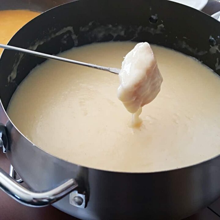 Fork with a chunk of bread dripping cheese fondue.