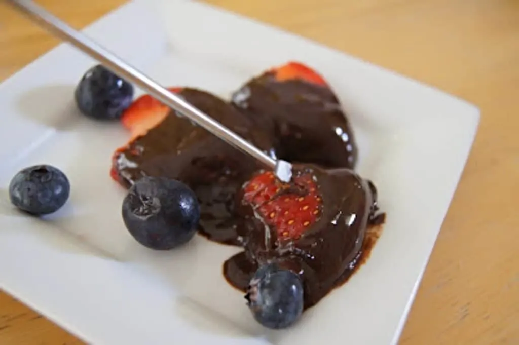 Strawberries dipped in chocolate with fondue fork.
