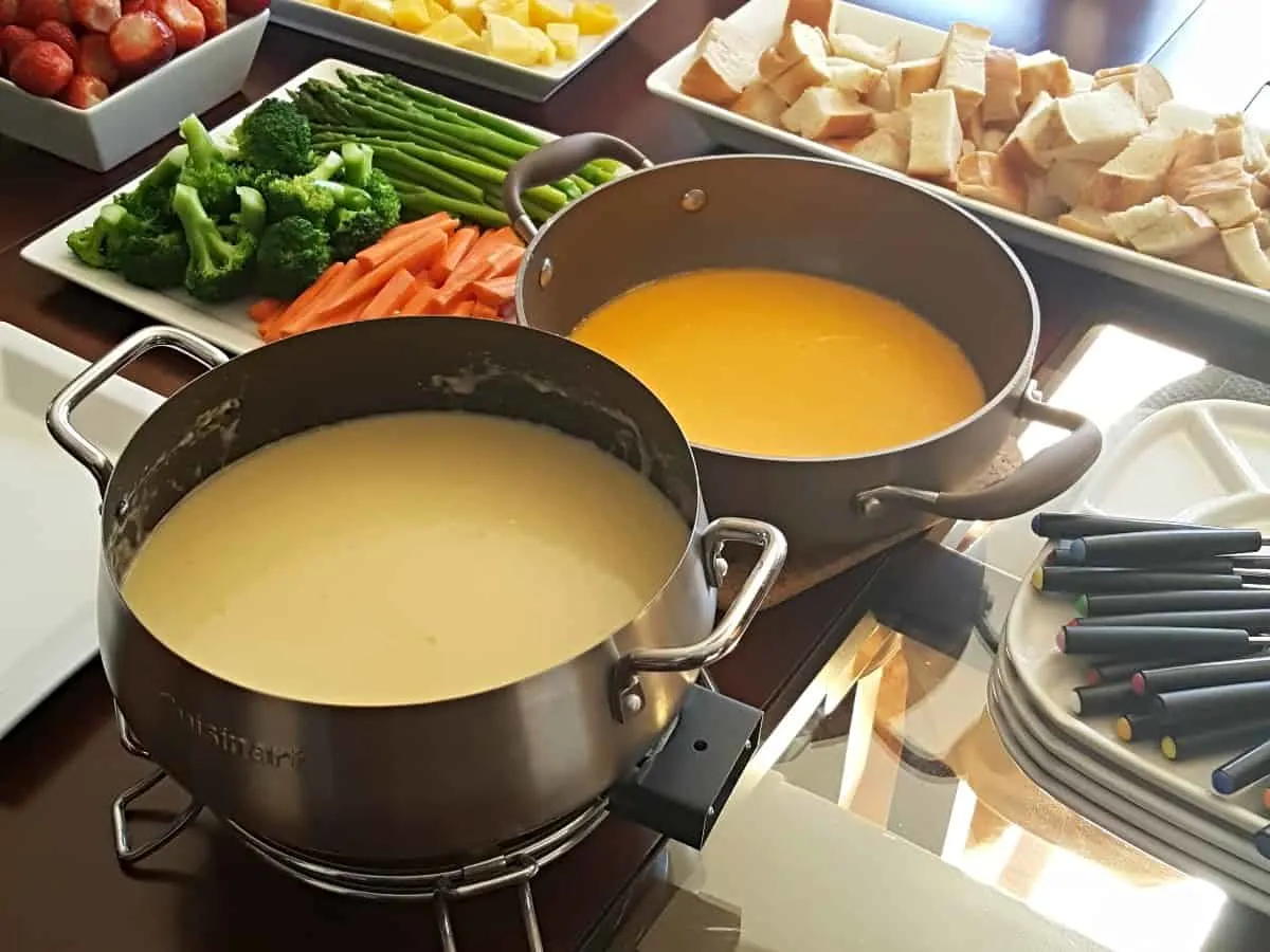 Traditional cheese fondue setup with pots veggies and bread.