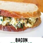 Bacon egg salad sandwich on a plate with wooden background.