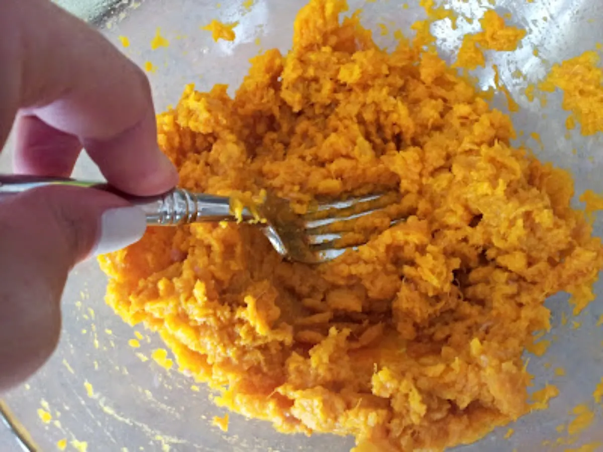 Mashing sweet potato in a bowl.