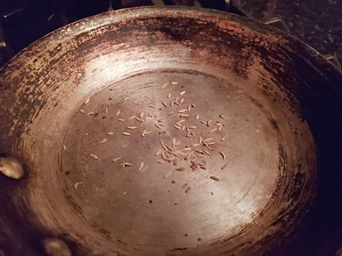 Toasting cumin seeds in a dry pan.