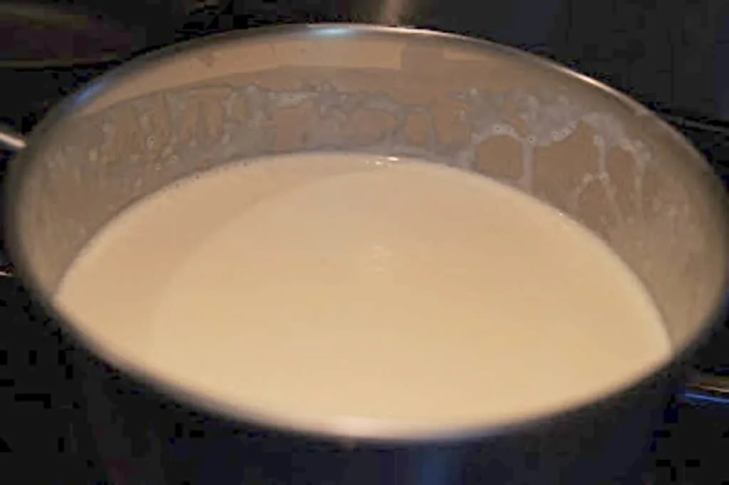 Cream being scalded in a small pot.