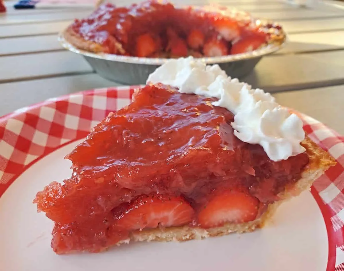 Slice of fresh strawberry pie on a paper plate.