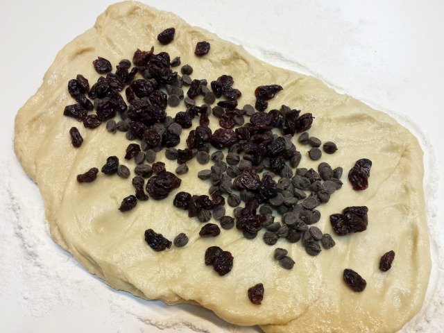 Add chocolate chips and cherries to the top of your once risen challah dough