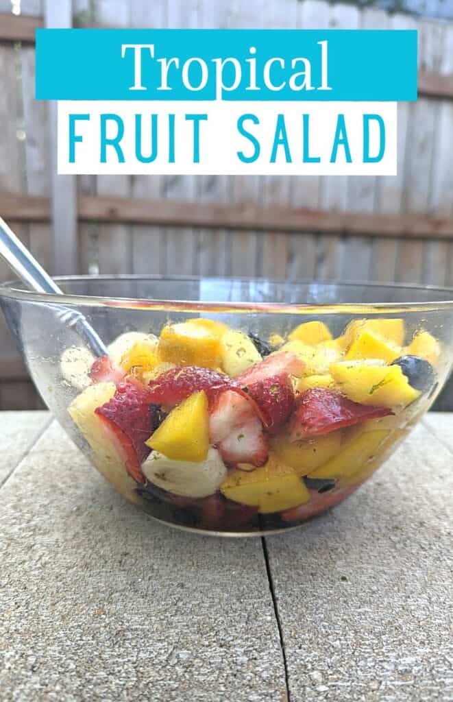 Image shows a Bowl with tropical fruit salad and text tropical fruit salad.