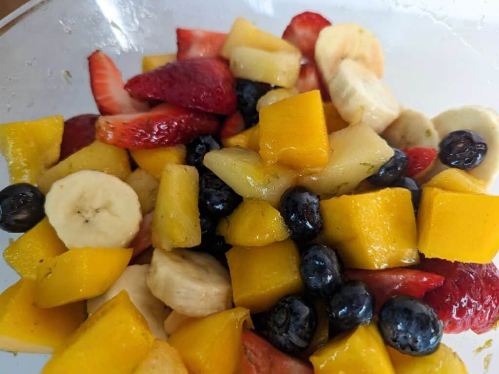 Image shows an Overhead shot of tropical fruit salad in a clear bowl.