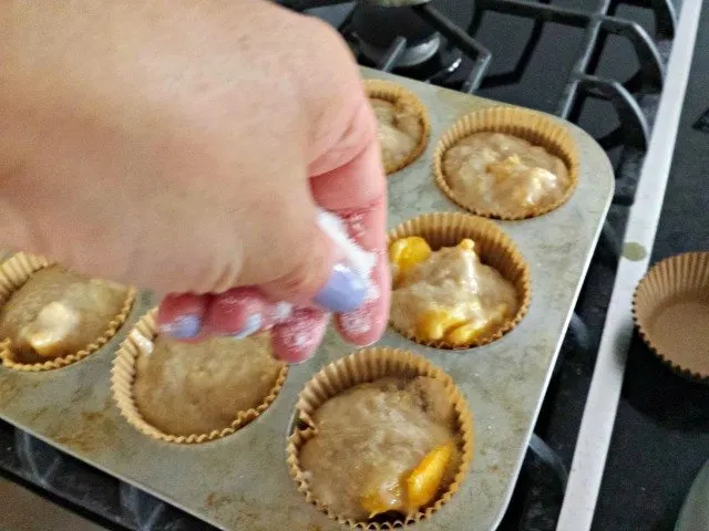 Sprinkle sugar over peach kuchen muffins just before baking