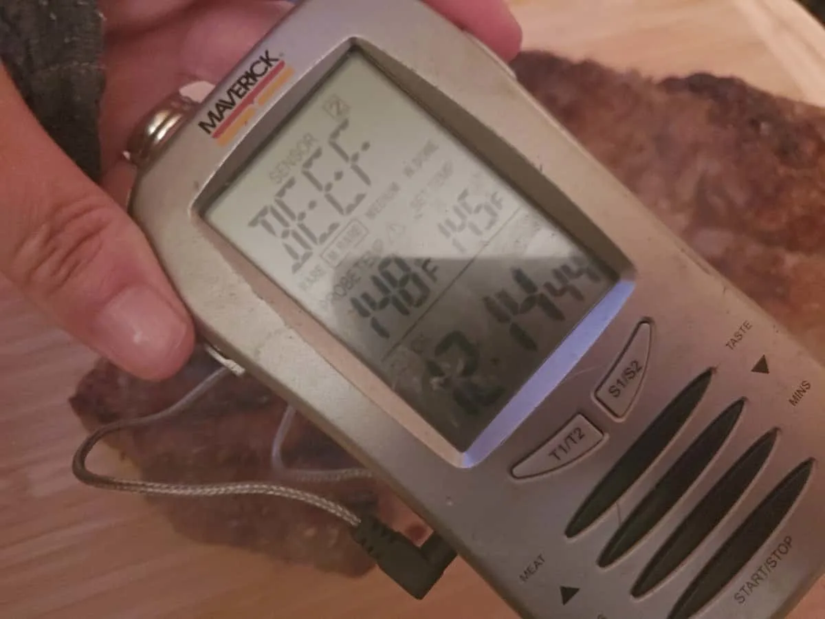 Digital temperature gauge measuring steak doneness.