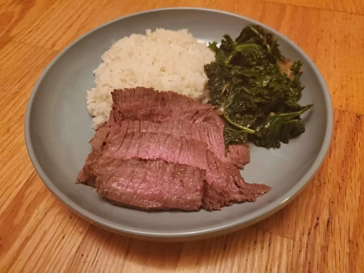 Plate of Asian marinated steak with rice and kale.