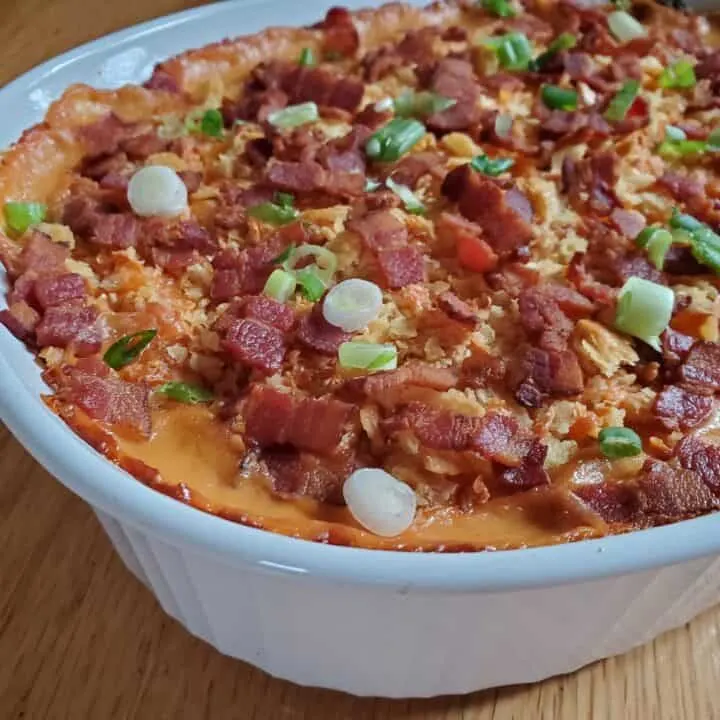 Closeup of corn casserole topped with bacon and green onion.