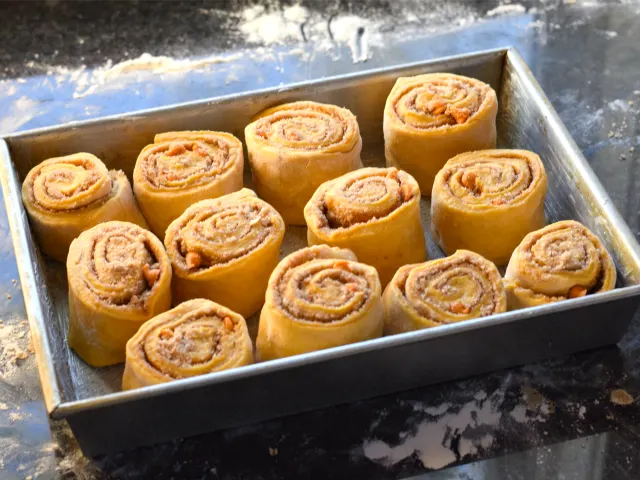 Stack pumpkin cinnamon rolls in your buttered pan