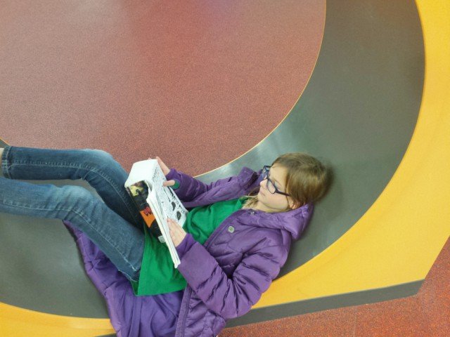 Girl reading a book in a circular hole.