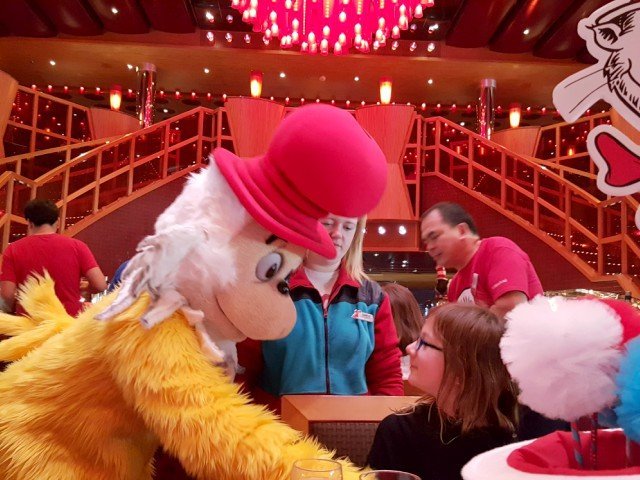Dr Seuss character greeting a girl at a breakfast table in a dining room.
