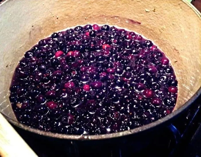 Simmering blueberry syrup in a pot.