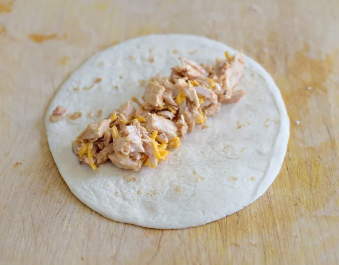 Add filling to homemade chicken enchiladas