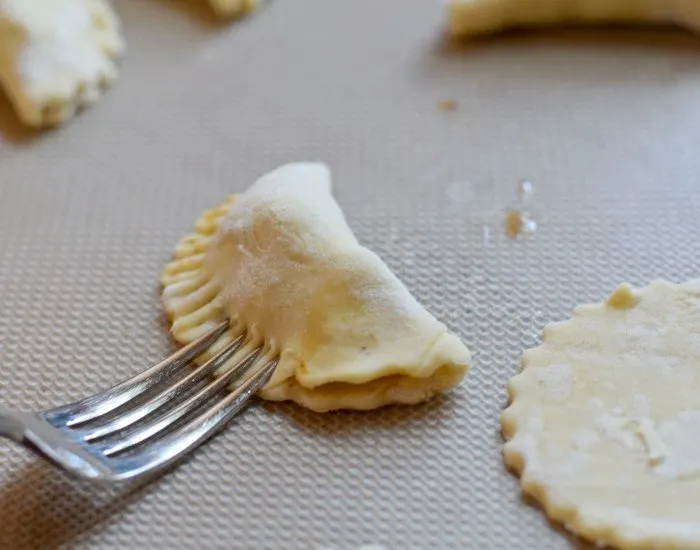 Crimp the edges of empanadas with a fork to seal