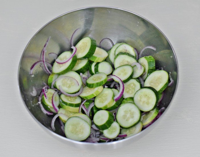 Add cucumbers onion and salt to bowl then cover with ice