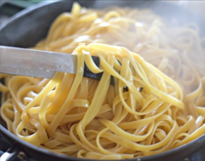 Use tongs to toss pasta to create cacio e pepe sauce