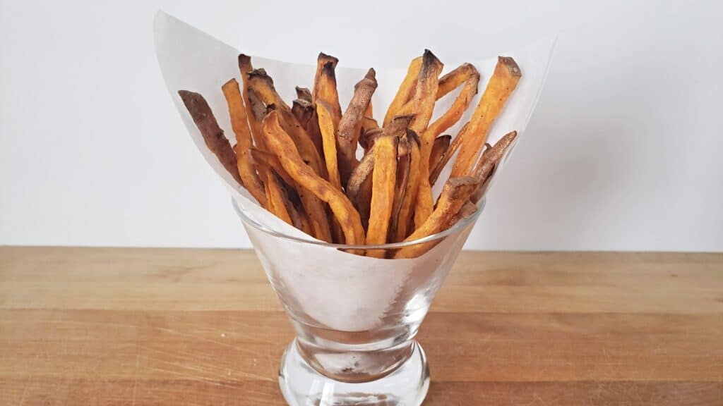 Basket of sweet potato fries in a clear glass.