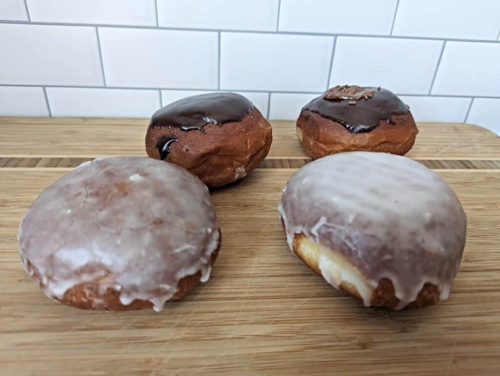 Four paczki on a board from Hanna's Bakery and Cafe.