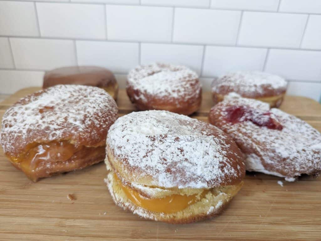 Six paczki from Country Style Donuts sitting on a wooden board.