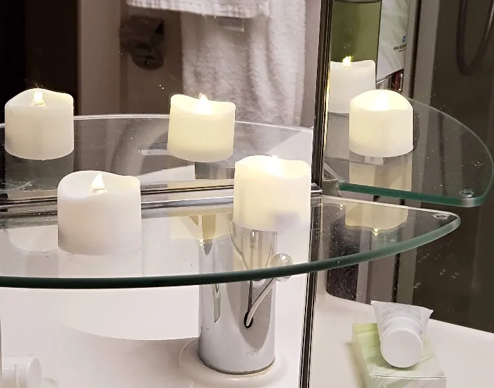 LED tea light candles on a shelf in a mirrored bathroom.