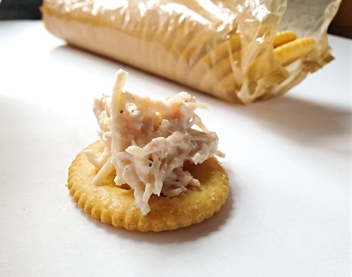 Crackers with chicken salad sitting on a white background.