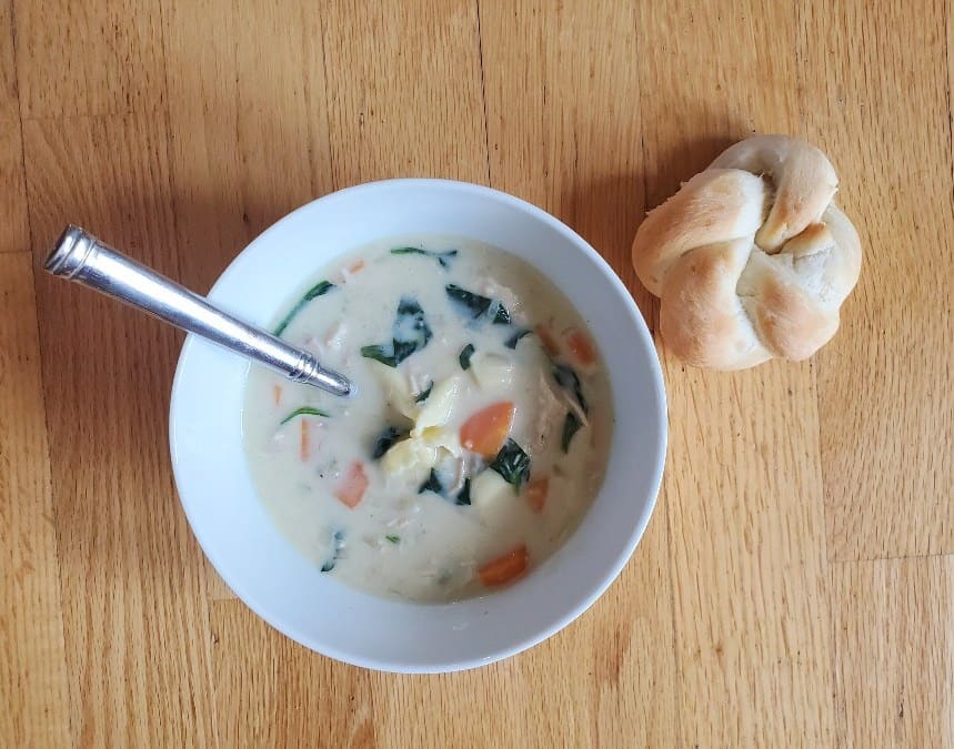 Bowl of creamy soup with a dinner roll