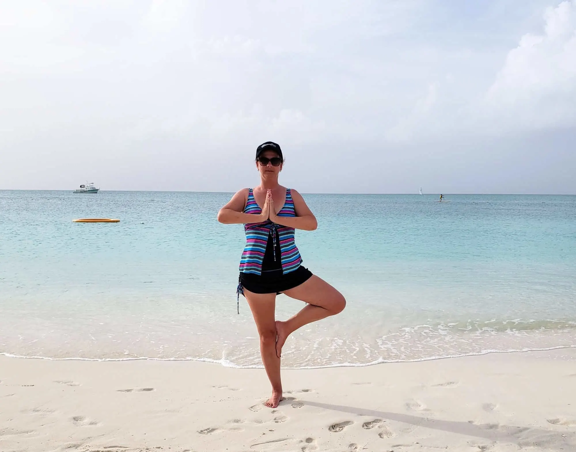 Woman doing yoga tree pose on the beach.