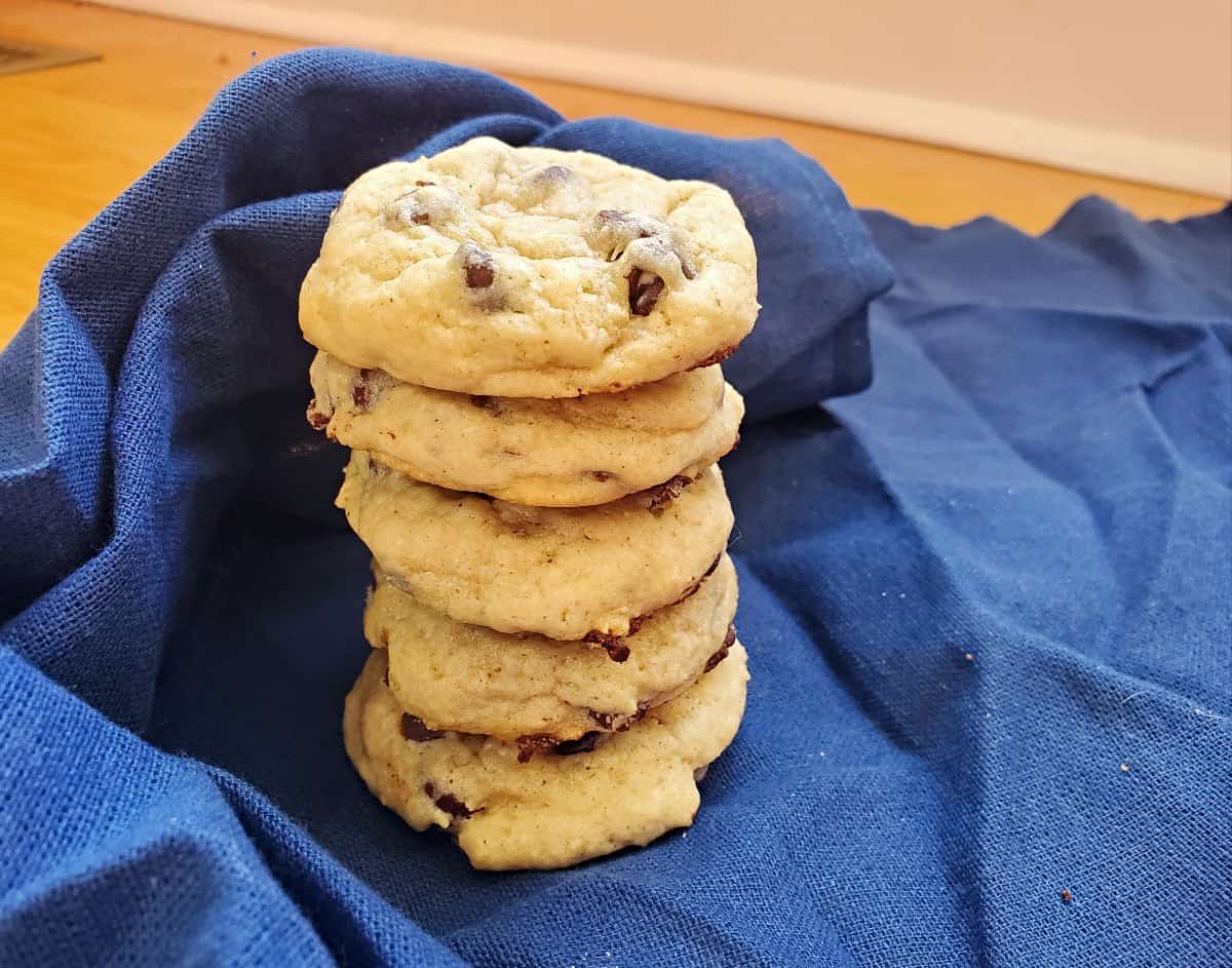 Image shows A stack of sourdough chocolate chip cookies on a blue cloth.