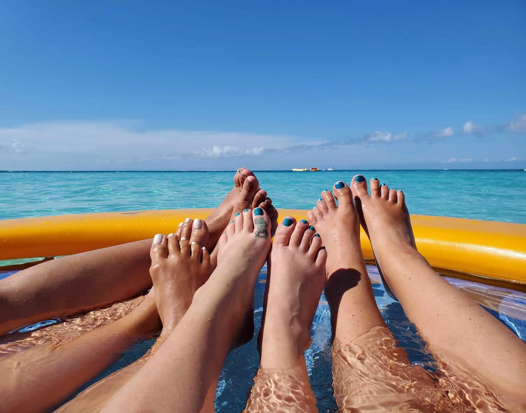 Women's legs and toes in a float in the ocean.