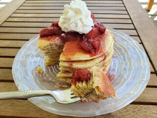 Plate of sourdough pancakes with strawberry syrup and whipped cream