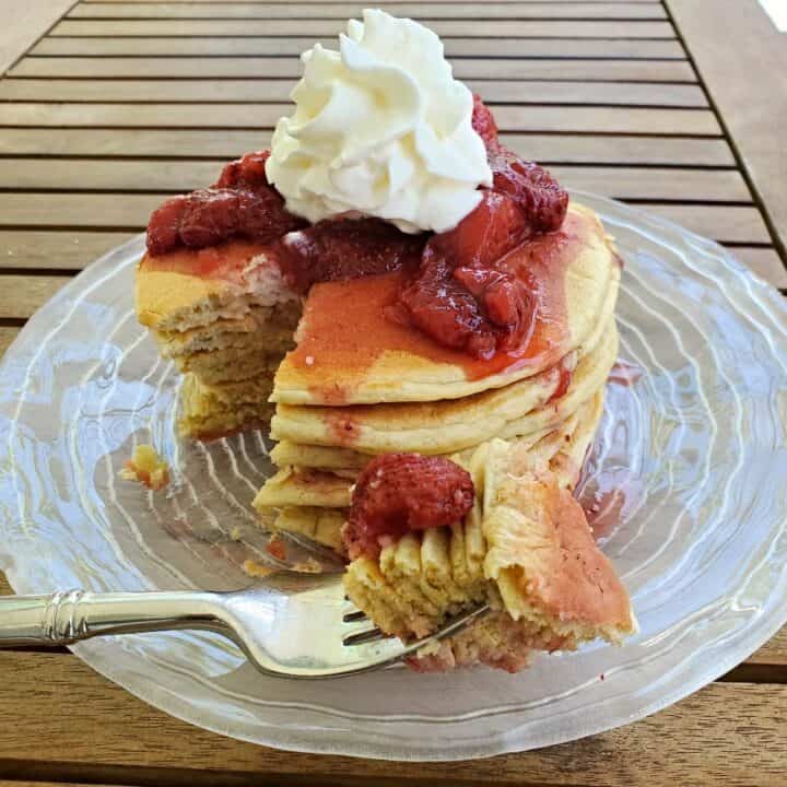 Plate of sourdough pancakes with strawberry syrup and whipped cream