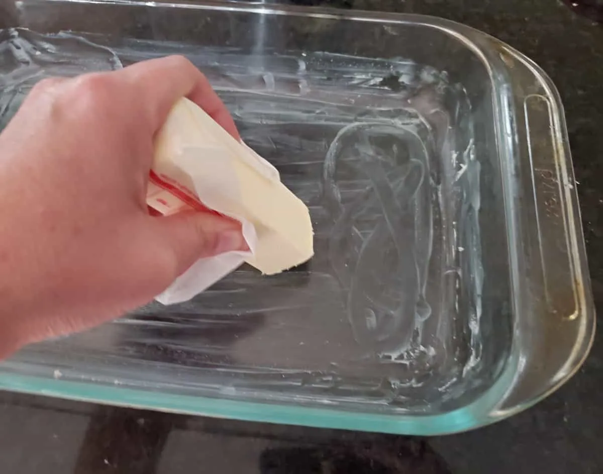 Buttering a glass baking dish.