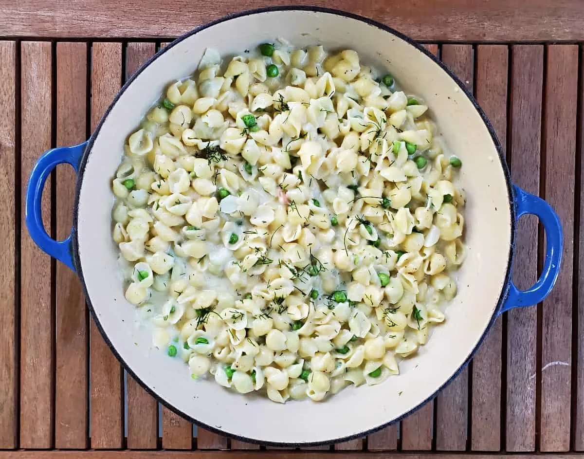 Pot of creamy pea pasta on a wooden table.