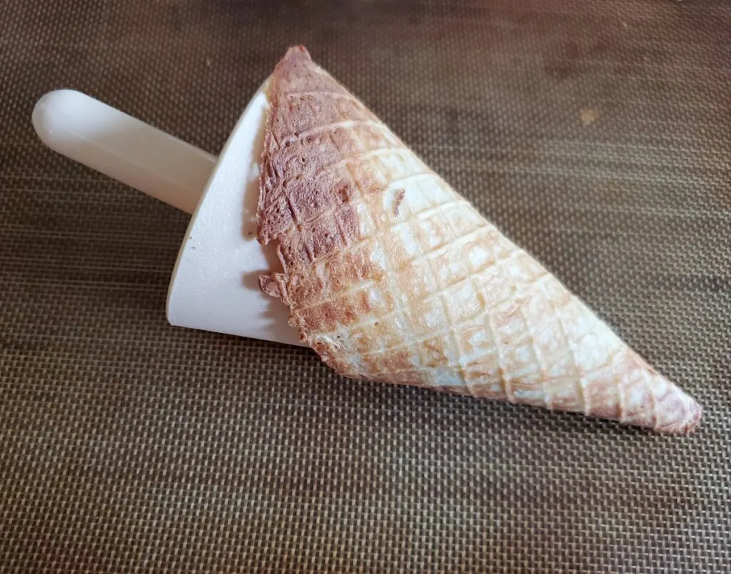 Image shows a Waffle cone on the roller lying on its side on a silpat.