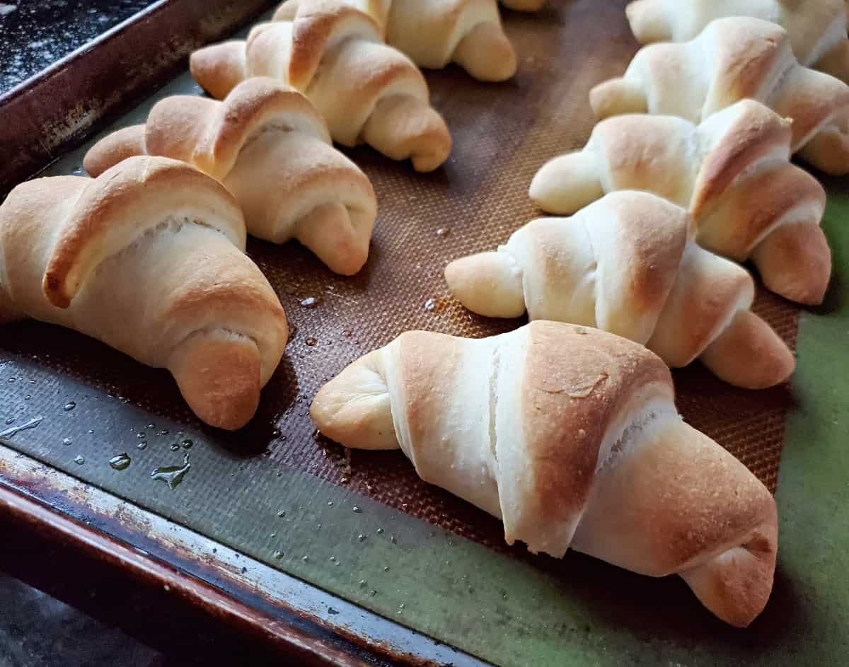 Fresh baked crescent rolls on a baking sheet.