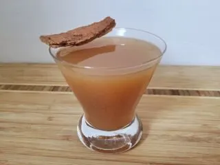 Hot apple cider rum in a cocktail glass topped by a cinnamon stick.